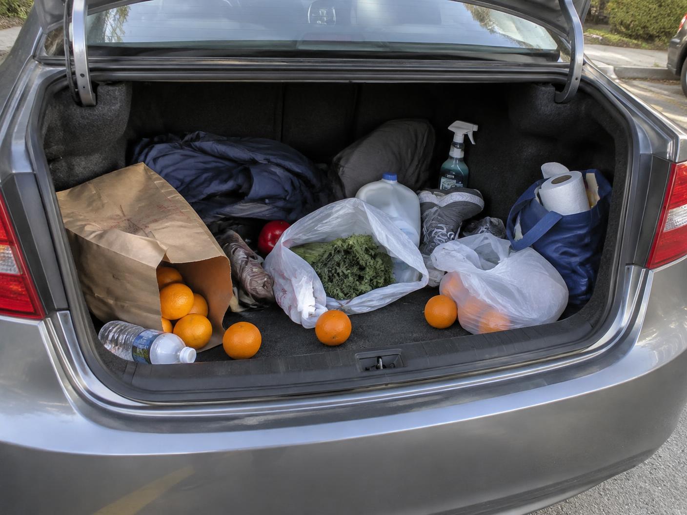 A cluttered SUV trunk with loose grocery bags and everyday items before using the organizer